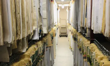 Archive plans hanging on both sides of walk aisle.