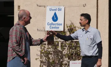 A community member returns motor oil to a Used Oil Collection Center