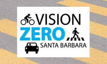 This image shows a crosswalk with a black and blue graphic that says "Vision Zero Santa Barbara," with illustrations of a biker, pedestrian and a car. 