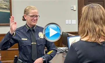 Chief Kelly Ann Gordon taking the Oath of Allegiance with her right hand in the air in her police uniform in Council Chambers