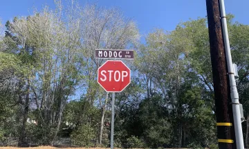 A stop sign below the street sign that says Modoc