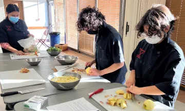 Three participants of the Chef Apprentice Program prep ingredients