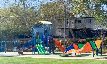 Image shows playground equipment in primary colors at a local park