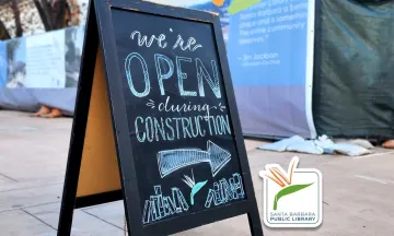 Graphic depicts a chalkboard sign on a sidewalk that reads "we're open during construction"