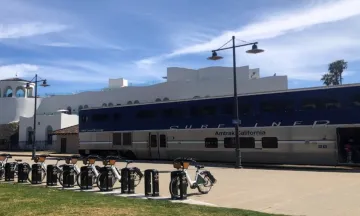 Image shows a row of ebikes in front of the Surfliner train