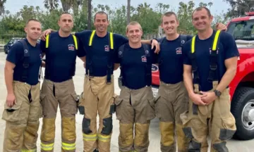 Image shows six firefighters in gear, smiling for a photo