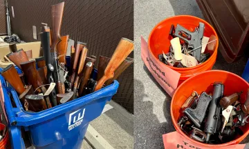 Image shows a garbage can filled with donated riffles and two buckets filled with handguns collected at the Gun Buy Back