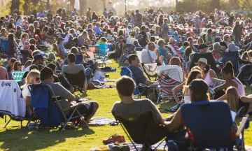 A group of people sitting on the lawn for a concert