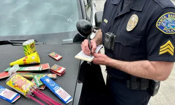 An SBPD officer writes a ticket with fireworks on the dashboard