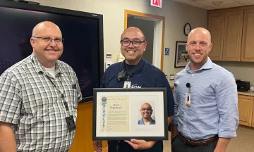 Scott poses with airport staff holding his EOM plaque 