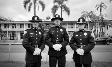Image shows three officers in uniform solemnly looking at the camera, black and white photo