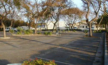 Image of Carrillo Commuter Parking Lot from Carrillo Street looking West, empty and clean parking lot with trees and fallen leaves on the ground throughout the parking lot