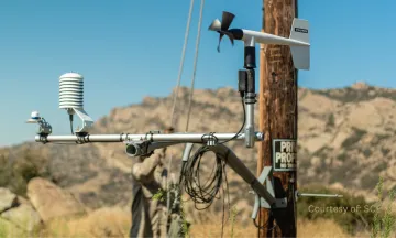 Image shows a power line with a crew member in the background working