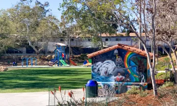 Image shows a City Park with a mural and playground equipment.