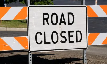 Image of an orange and white sign that reads "Road Closed" 