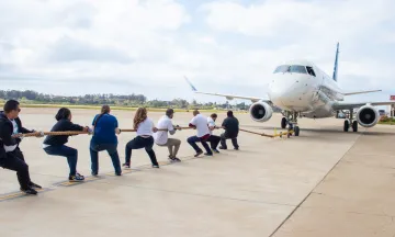 A group of people pull a rope attached to an Alaska Airlines plane at the Santa Barbara Airport.