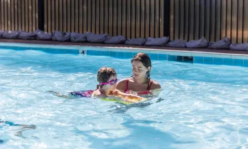 Swim instructor guides a young swimmer as they learn to kick