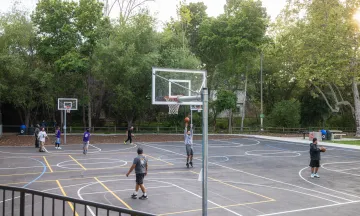 Community members play basketball on the new court at Bohnett Park