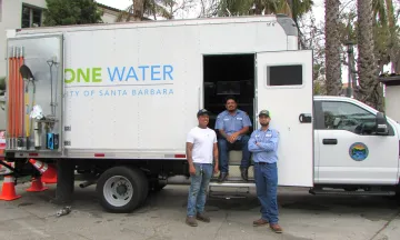 Public Works employees standing in front of a One Water service truck.