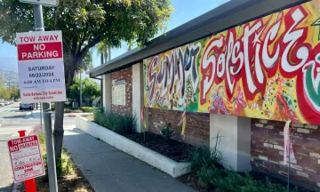 No Parking sign in front of a colorful Summer Solstice banner.