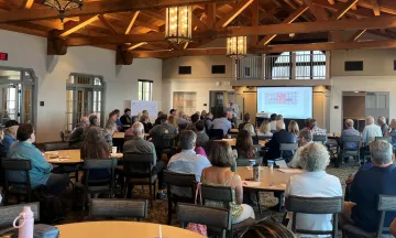 Community meeting with residents viewing a powerpoint presentation in the main room of the Cabrillo Pavilion