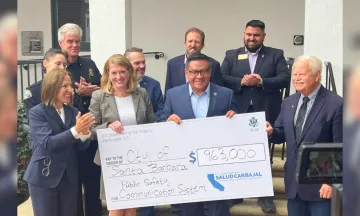 Kelly McAdoo and Rep Carbajal holding a large check surrounded by representative from City Fire-Police-Information Technology