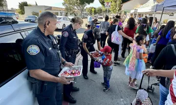 Chief Gordon and Officer Adrian Gutierrez  handing out candy at a community event.jpg