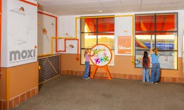 Three kids interact with the MOXI exhibit at SBA