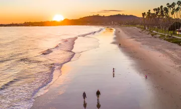 Beach at Sunset with people walking along the sand and pedestrian path.