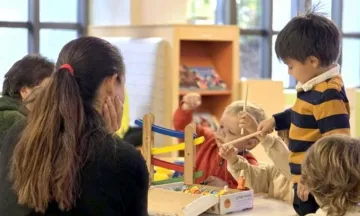 Children Playing with a toy on a table as an adult supervises.