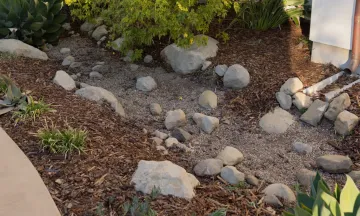 Photo of downspout emptying to gravel that helps with storm water management  and run off.
