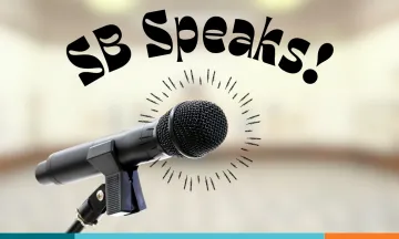 A microphone on a stand in the foreground with the text “SB Speaks!” above it on a transparent room background.