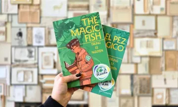 Hand holding the books The Magic Fish and El pez mágico