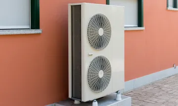 Outdoor heat pump unit with two large fans installed on a concrete base