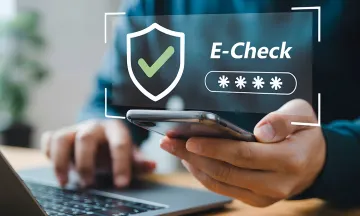 Person paying a bill online with a Smartphone and laptop