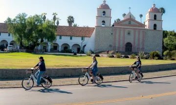 Three people riding BCycles in front of Old Mission Santa Barbara