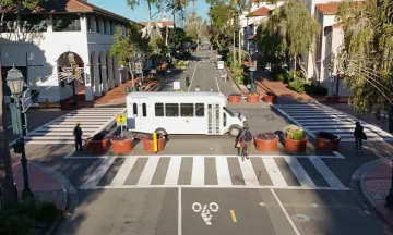 A bus traveling through the Carrillo intersection with pedestrians and cyclists waiting to cross.
