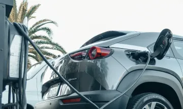 Stock image of grey electric vehicle plugged in to charge