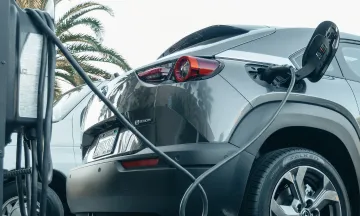 Stock image of grey electric vehicle plugged in to charger