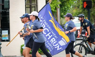 members of local law enforcement agencies run while carrying torch in symbolic support of special olympics
