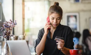 woman on the phone looking at a credit card