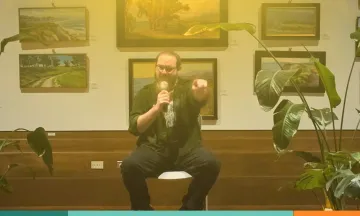 a person sits on a chair with a microphone 