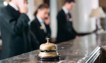 bell on the counter of a hotel check-in desk with staff in the background