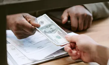 Person paying a bill at a counter with cash