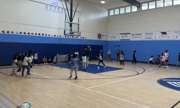 Many children in a gymnasium laughing and playing games with one another 