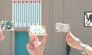 Library Cards being held up in front of the Central Library