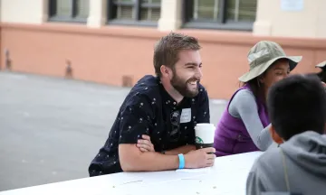 Man drinking coffee laughing with a group of friends
