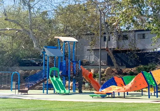 Image shows playground equipment in primary colors at a local park