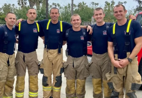 Image shows six firefighters in gear, smiling for a photo