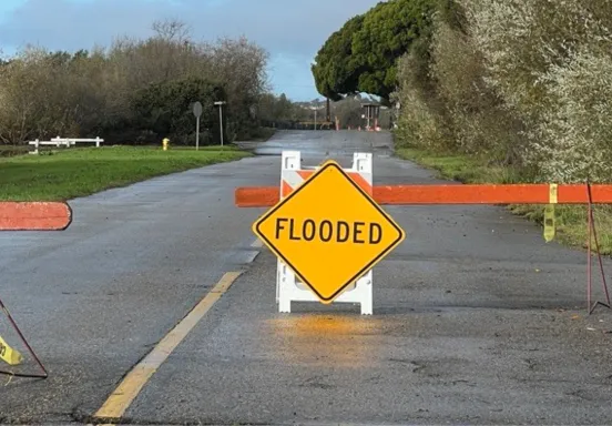 Road with a barricades and a sign that says "flooded"